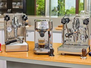 Three espresso machines on a kitchen countertop.