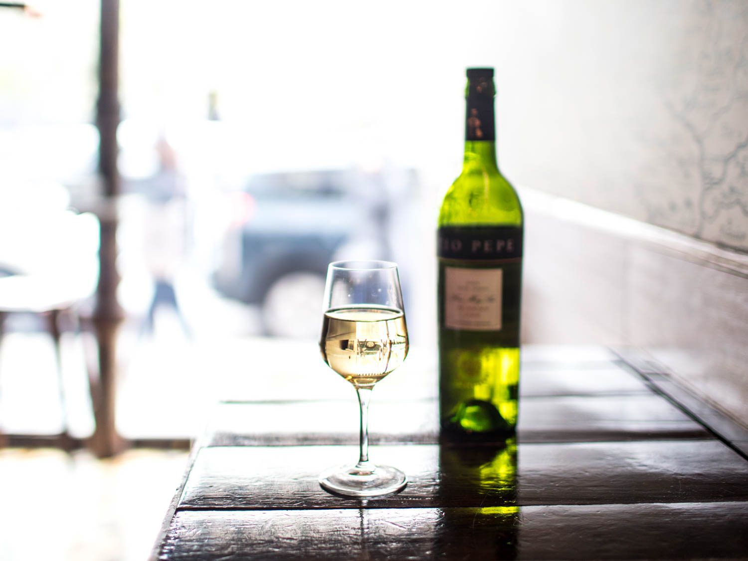 A wineglass of light-colored Fino sherry, with a bottle in the background