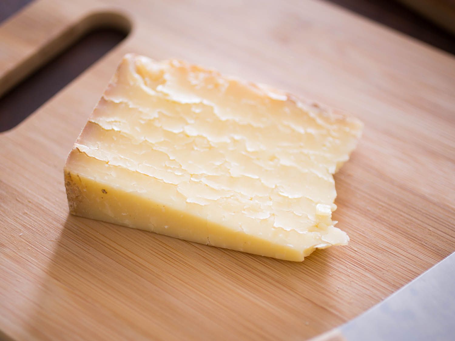 A flaky wedge of clothbound cheddar on a wooden board.