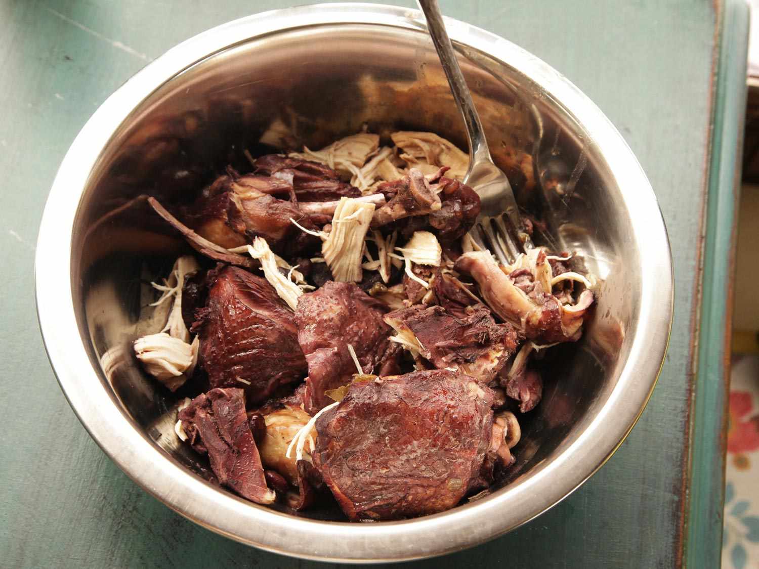 The stewed chicken is shredded in a prep bowl.