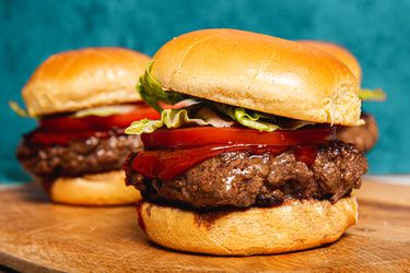 Wagyu burgers on a bun with ketchup, tomato and lettuce. 