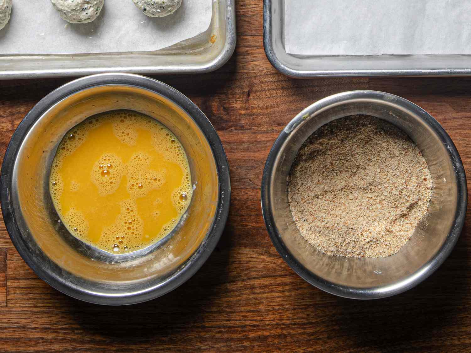 Overhead view of bowl of eggs and bowl of breadcrumbs