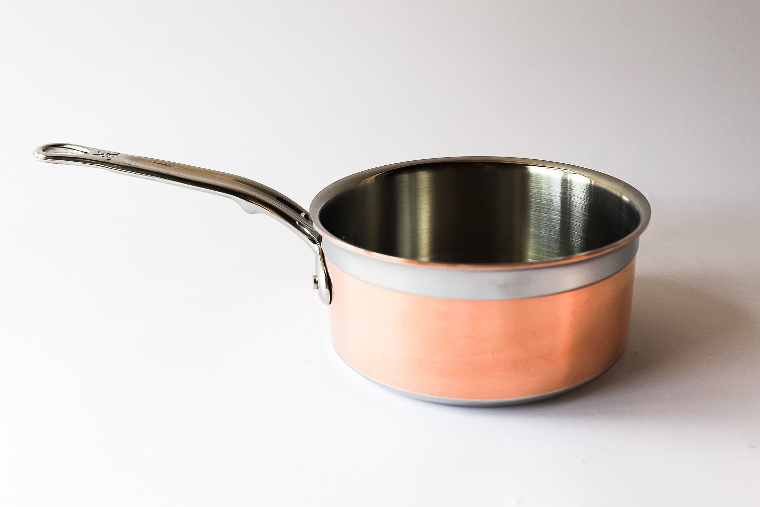A metal saucepan with a smooth handle and a polished interior on a plain background