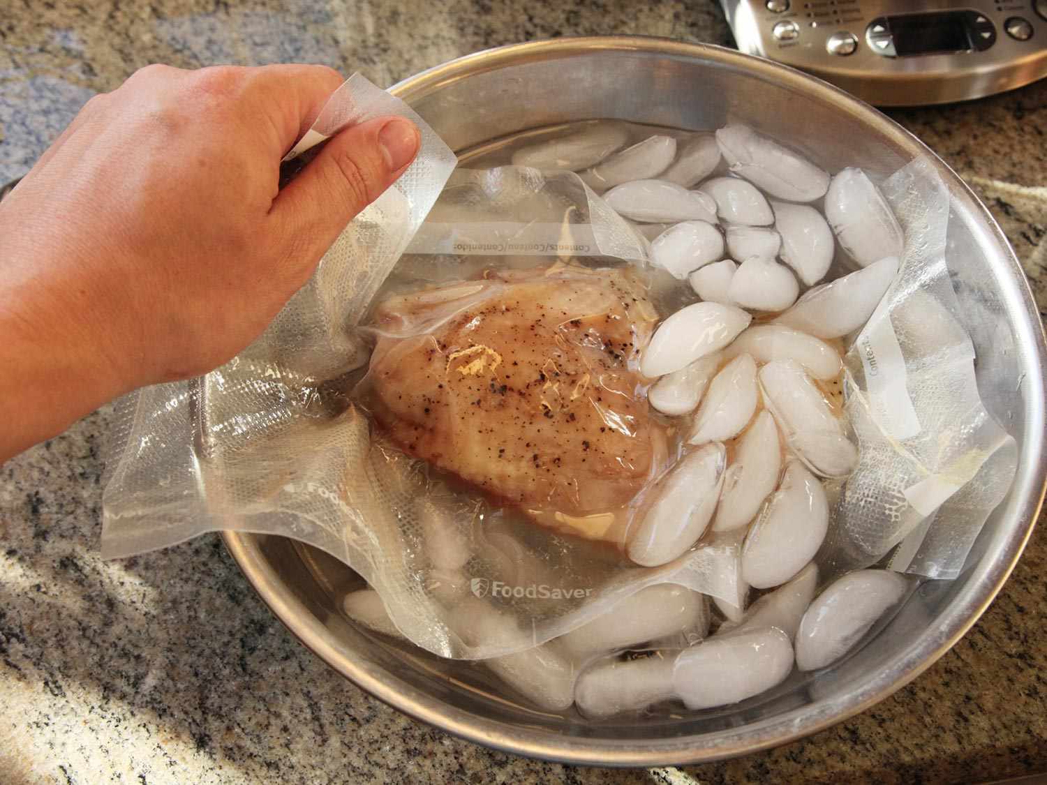 A piece of chicken in a vacuum-sealed bag being dropped in an ice bath.