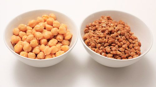 Two white bowls next to each other. One bowl holds chickpeas, the other holds lentils.