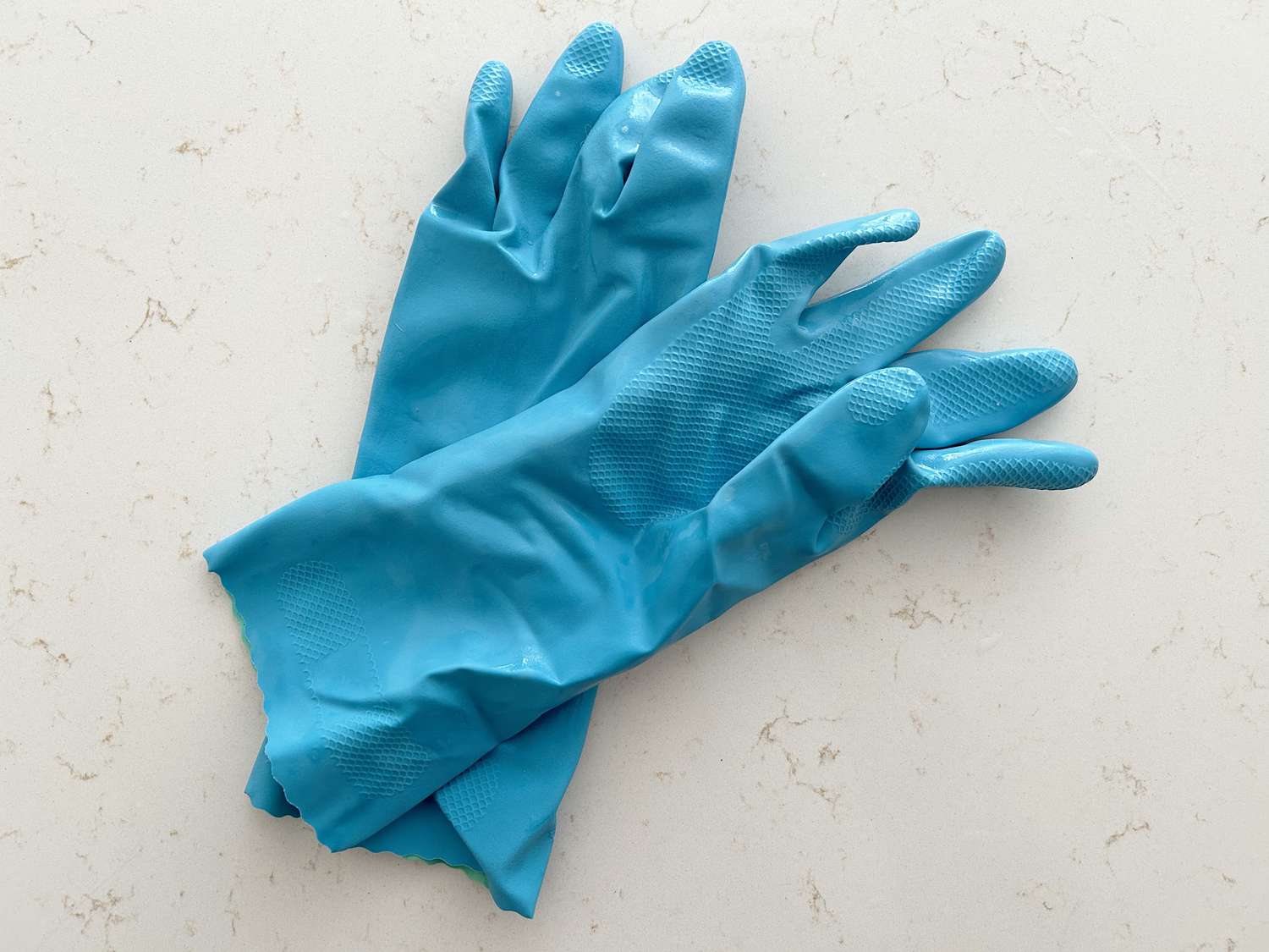A pair of blue dish gloves on a white counter