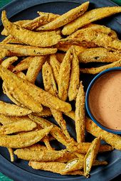 Dark blue plate with fried okra and a bowl of comeback sauce, on a deep green surface