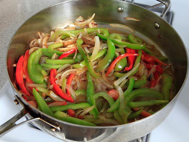 A sauté pan of onions and red and green peppers