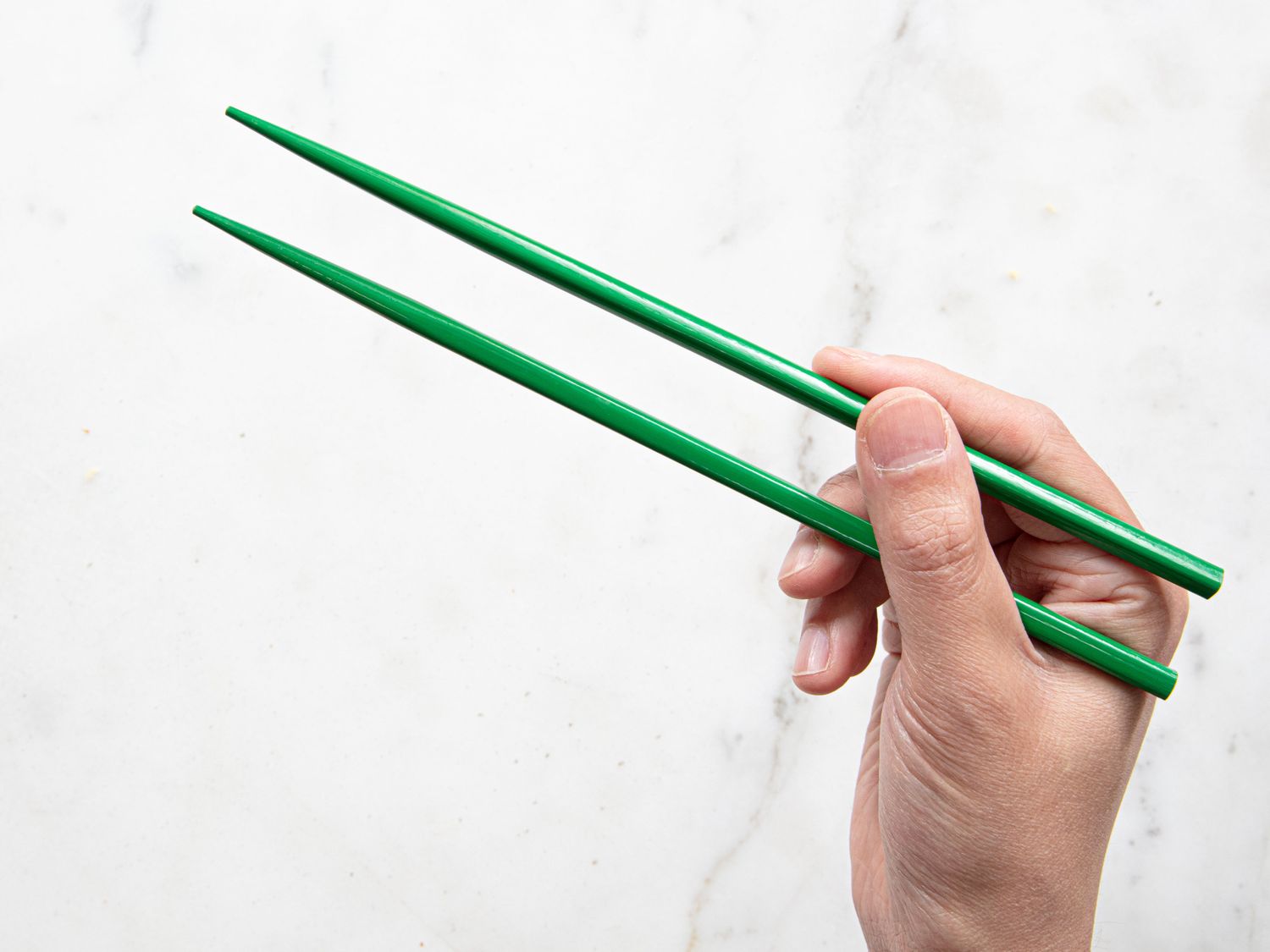 Hand demonstrating how to hold chopsticks