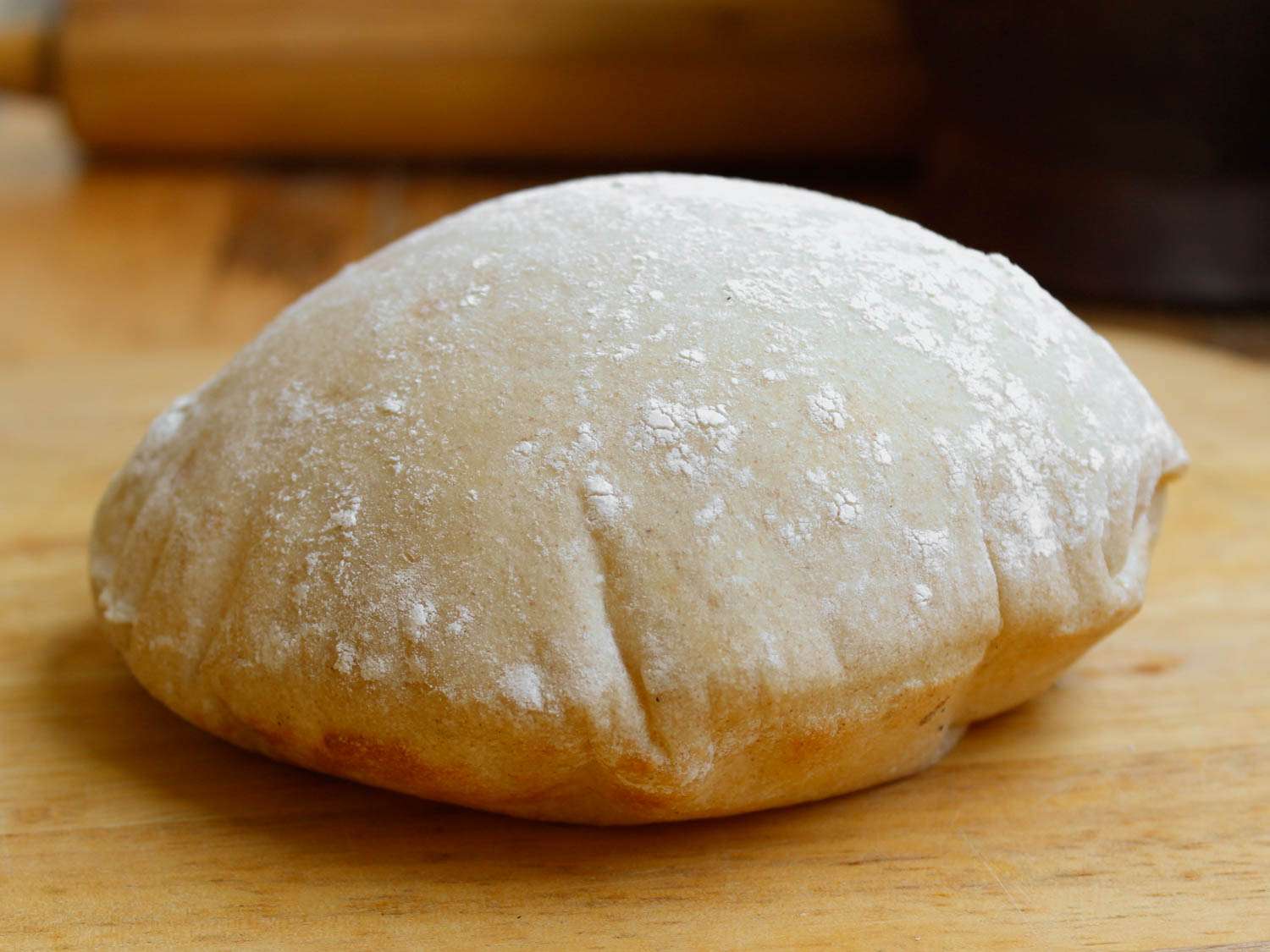 A perfectly puffed pita on a wooden surface.