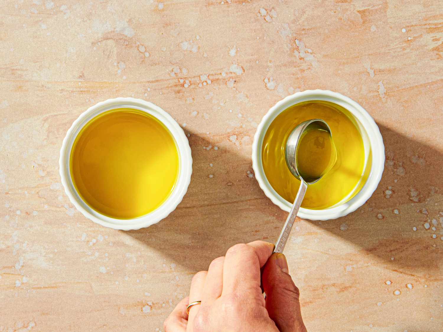 Two ramekins with yellow pudding a hand holding a spoon over the right ramekin