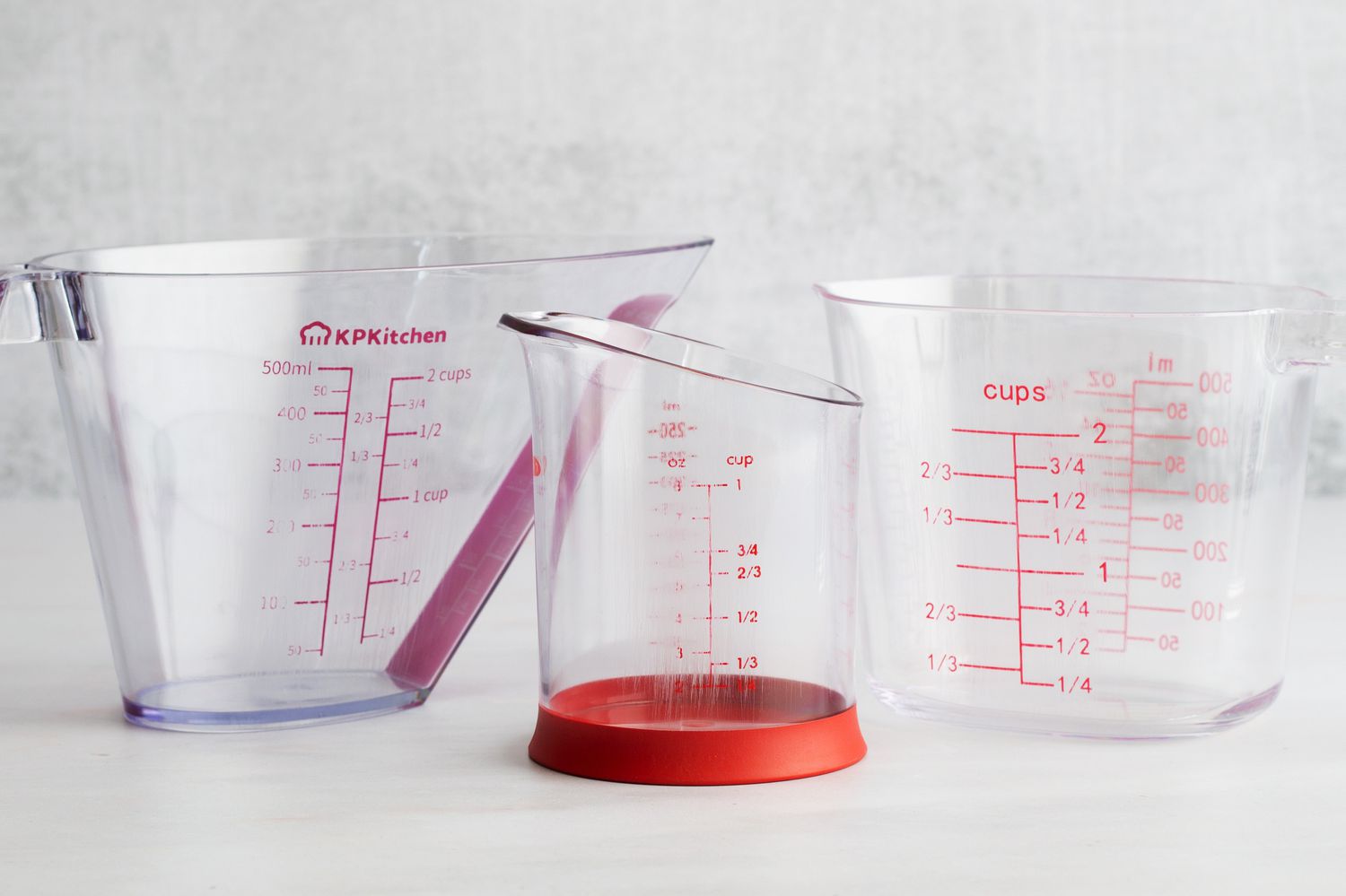 Three plastic liquid measuring cups on a countertop.