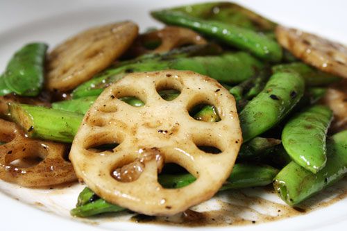 Close up of lotus root that has been stir fried with pea pods.