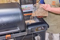 A person pours pellets into the Traeger Woodridge Pro