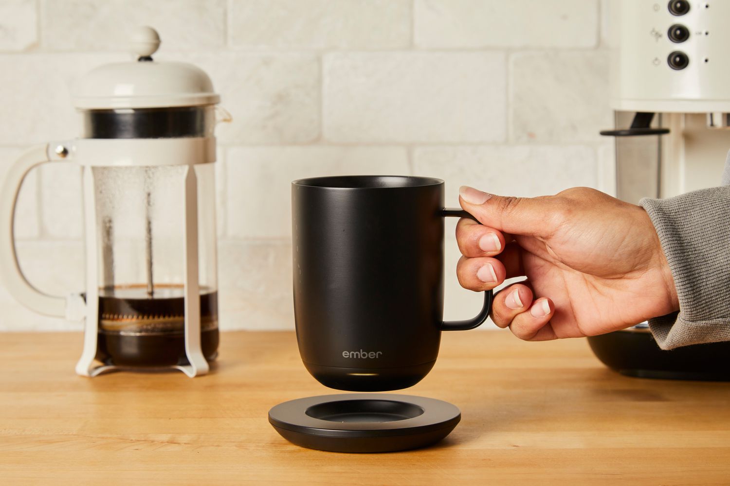 A person lifting the Ember coffee mug off its charging pad
