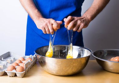 person cracking eggs into bowl