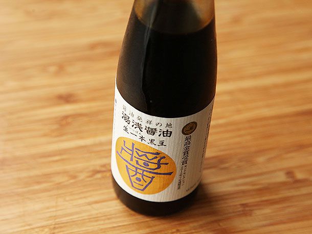 A bottle of shoyu on a wooden surface.