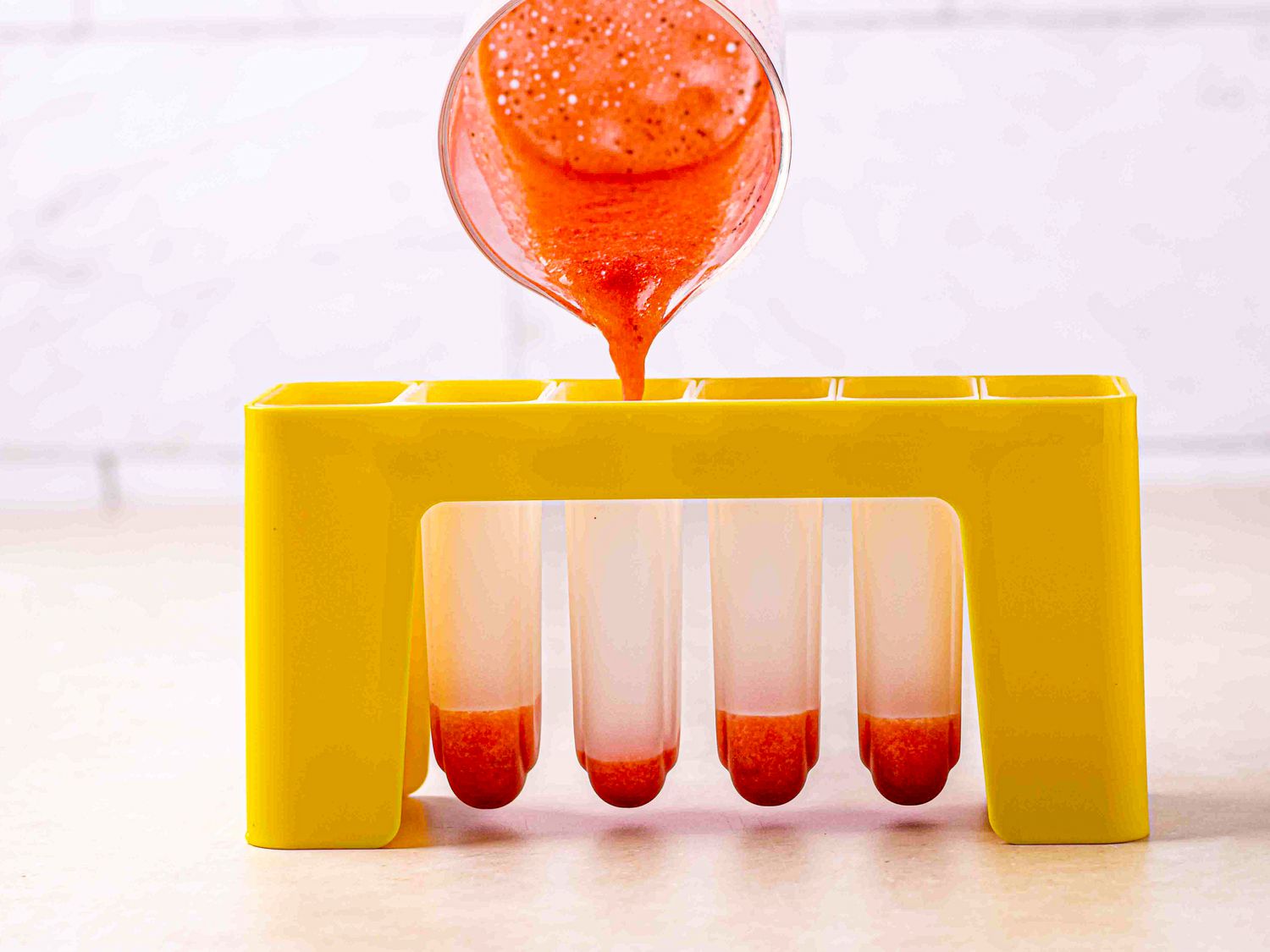 Side view of filling molds with strawberry puree