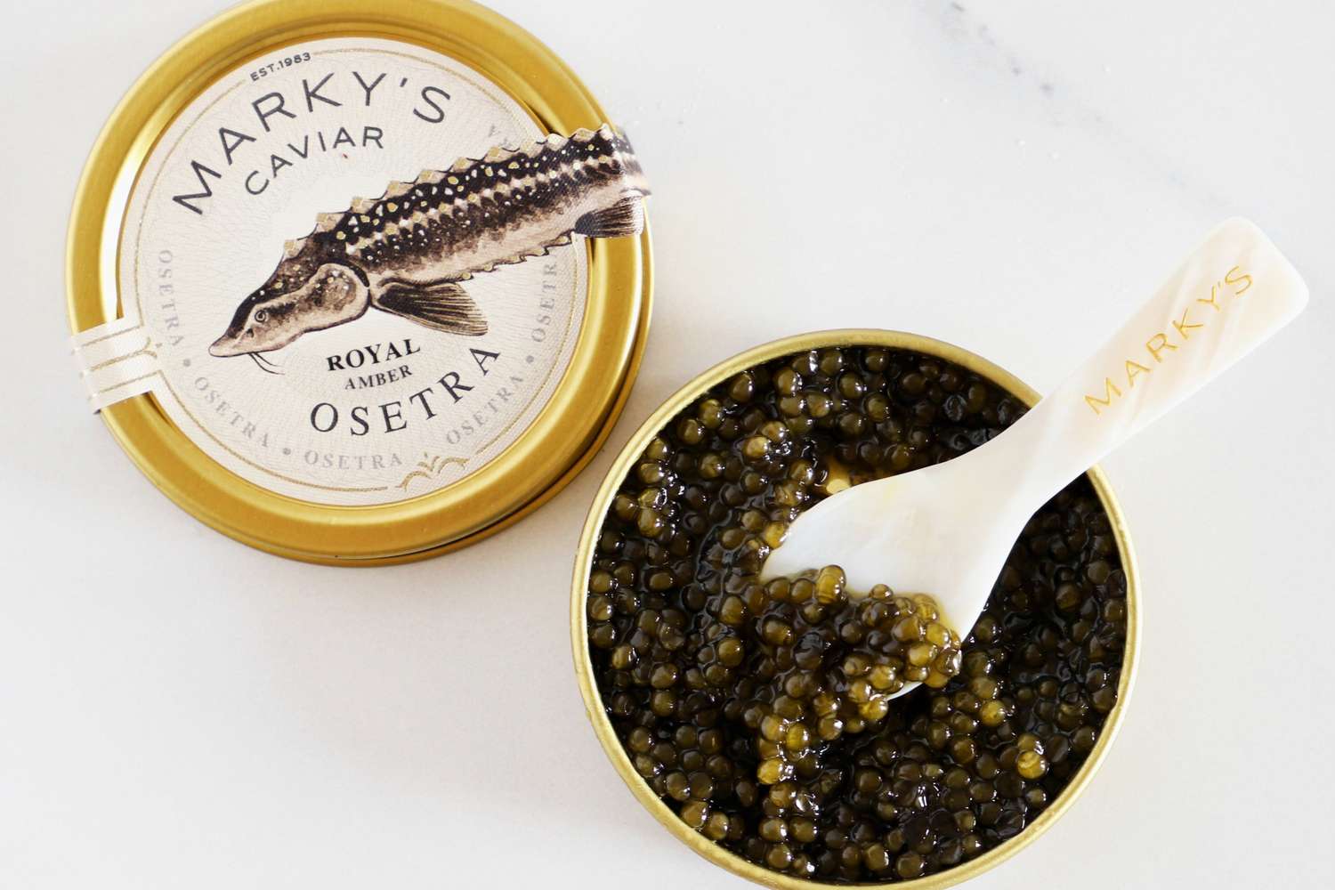 A tin of Marky's royal amber osetra caviar with a mother-of-pearl spoon inside