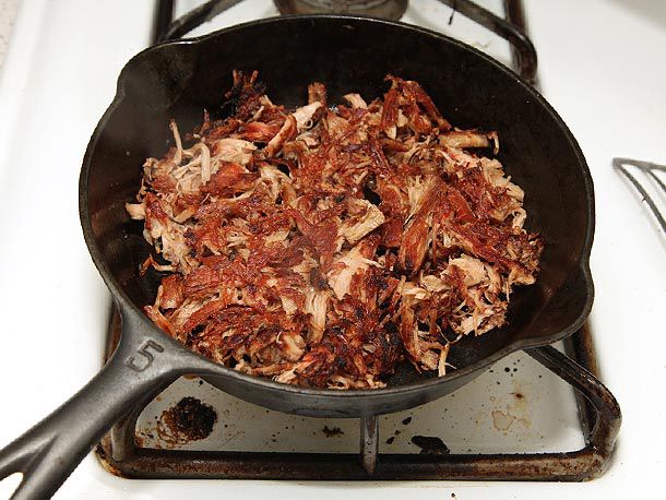 Shredded turkey meat crisping in a cast iron skillet. 