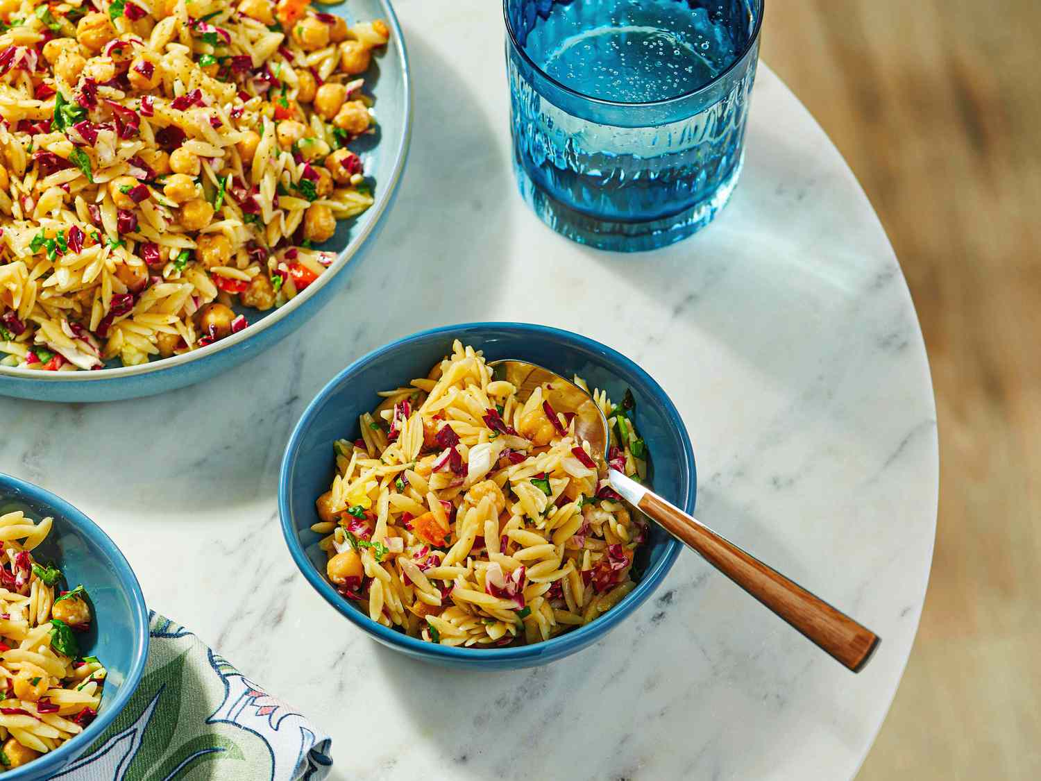 A bowl of lemon orzo pasta salad with mixed vegetables on a table