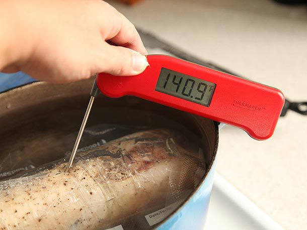 Testing internal temperature of stuffed chicken with instant-read thermometer