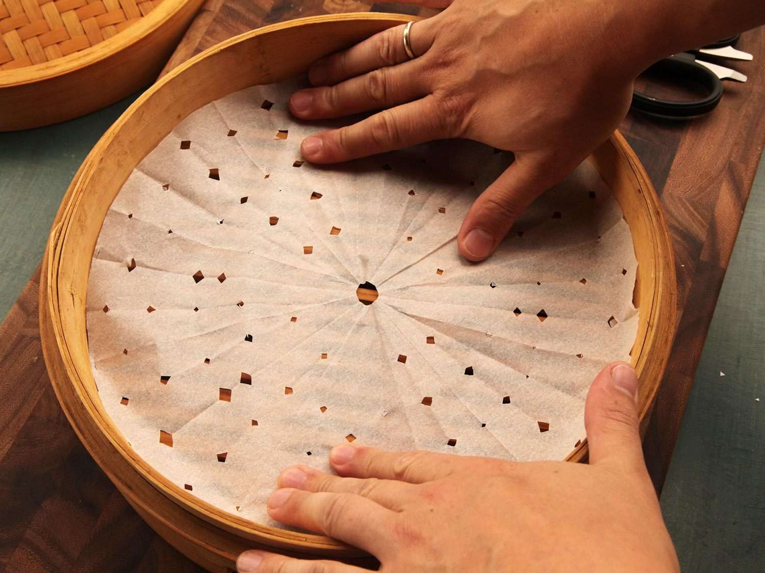 Placing parchment paper round in steamer basket that was cut to fit with vent holes.