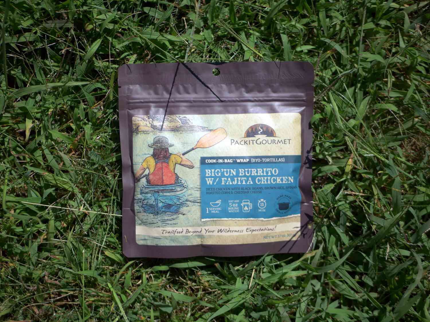 Package of Packit Gourmet Bigun Burrito with Fajita Chicken resting on grass