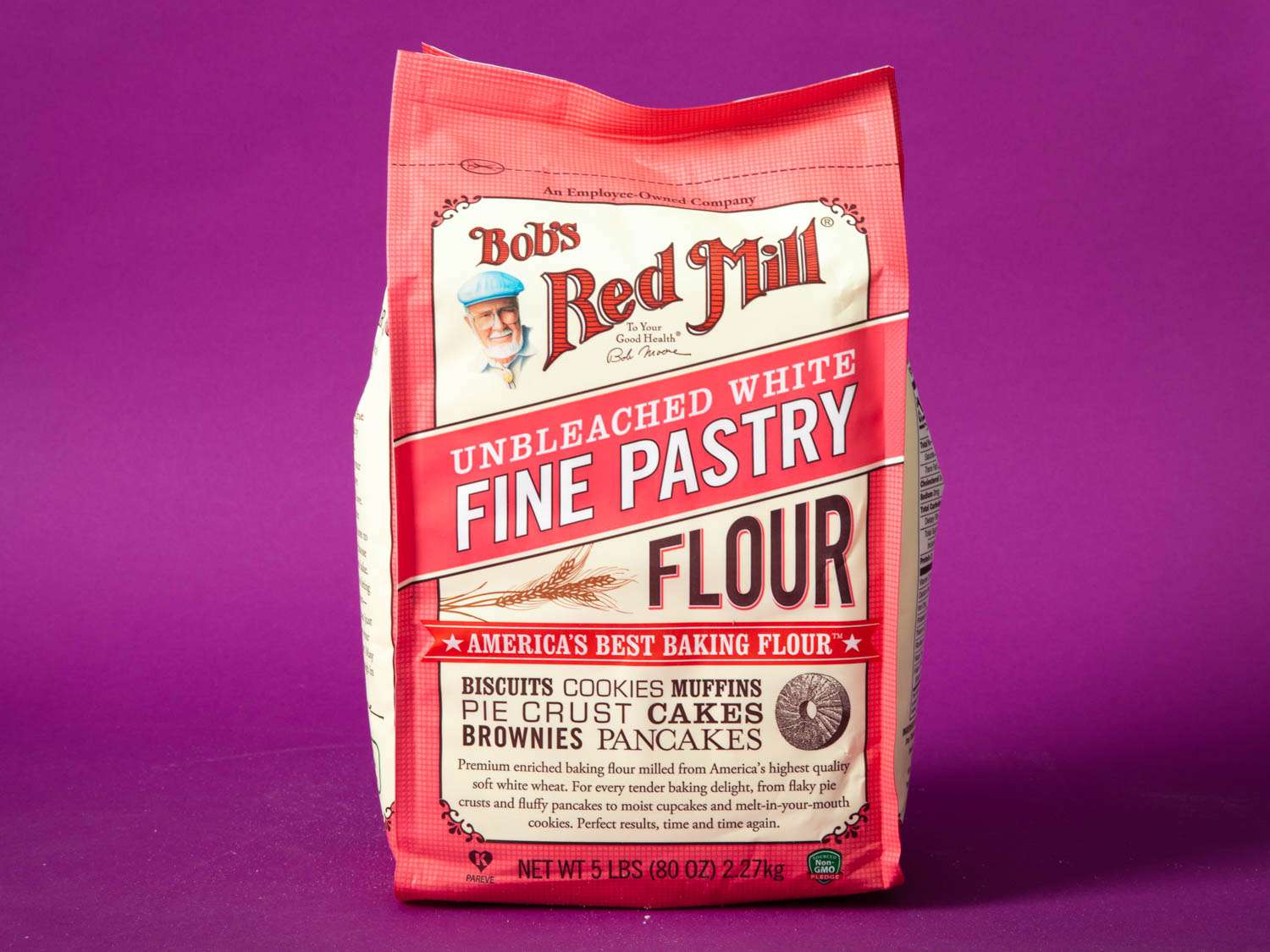 A bag of Bob's Red Mill Unbleached White Fine Pastry Flour against a purple background.