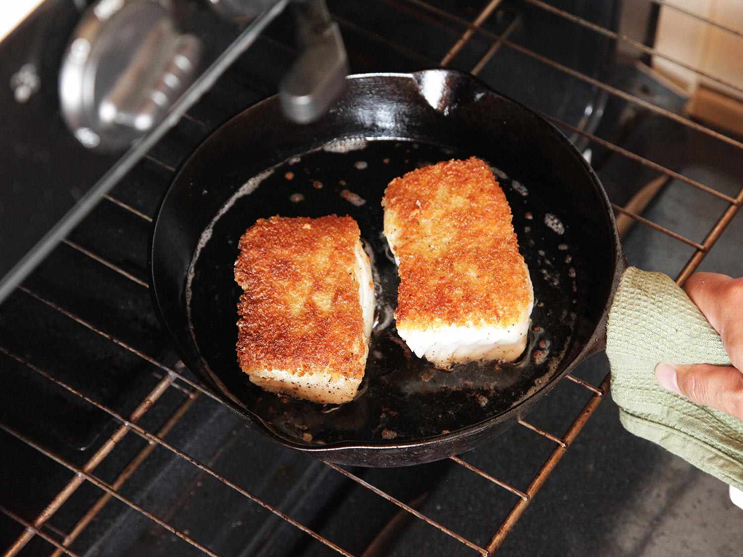 The skillet is transferred to the oven so that the fish can cook through.