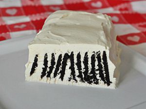 A whipped cream and chocolate wafer cookie ice box cake, sliced to show the cookies inside.