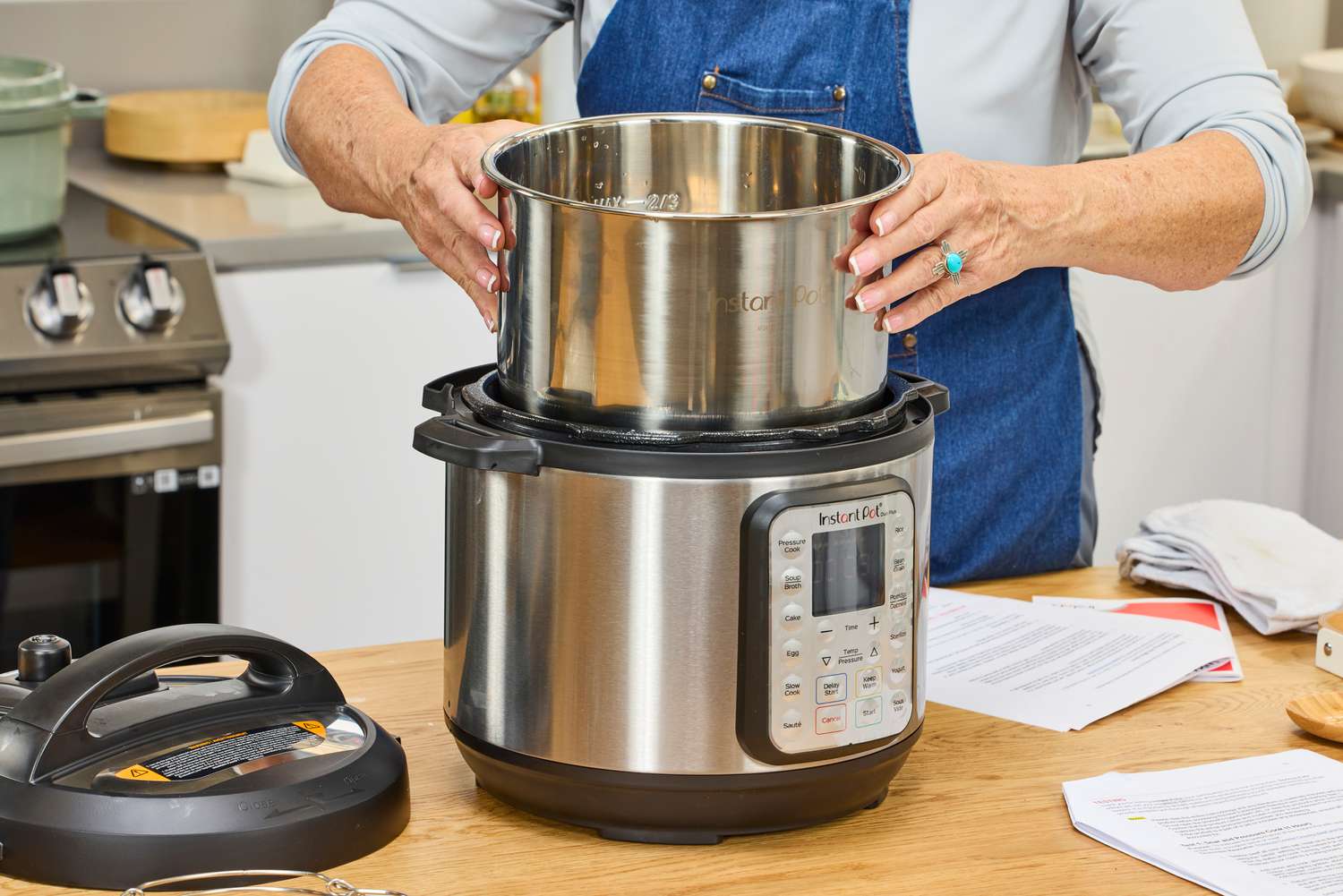 A person removes the inner pot from the Instant Pot Duo Plus 6-Quart 9-in-1 Pressure Cooker