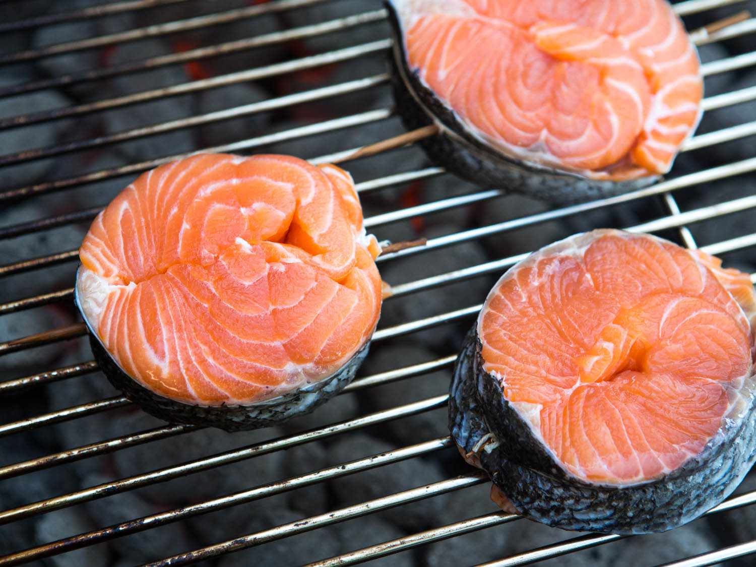 Three salmon steaks on the grill.