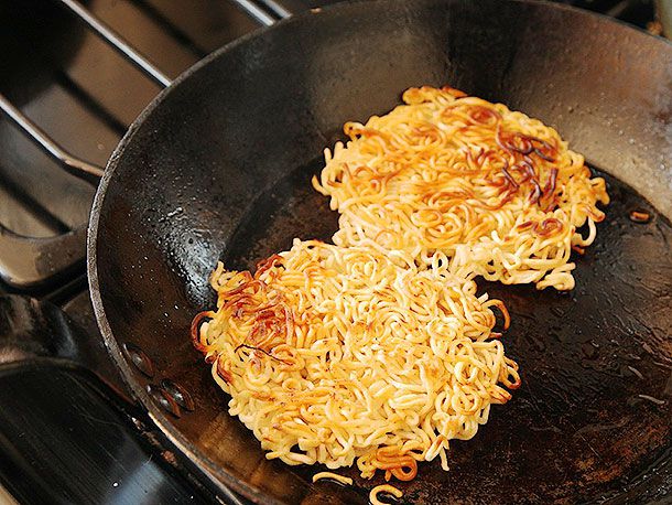 Two ramen disks browned on one side in a skillet.