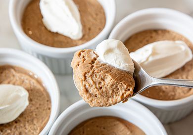 Bowls of pudding with whipped topping, spoon holding a serving