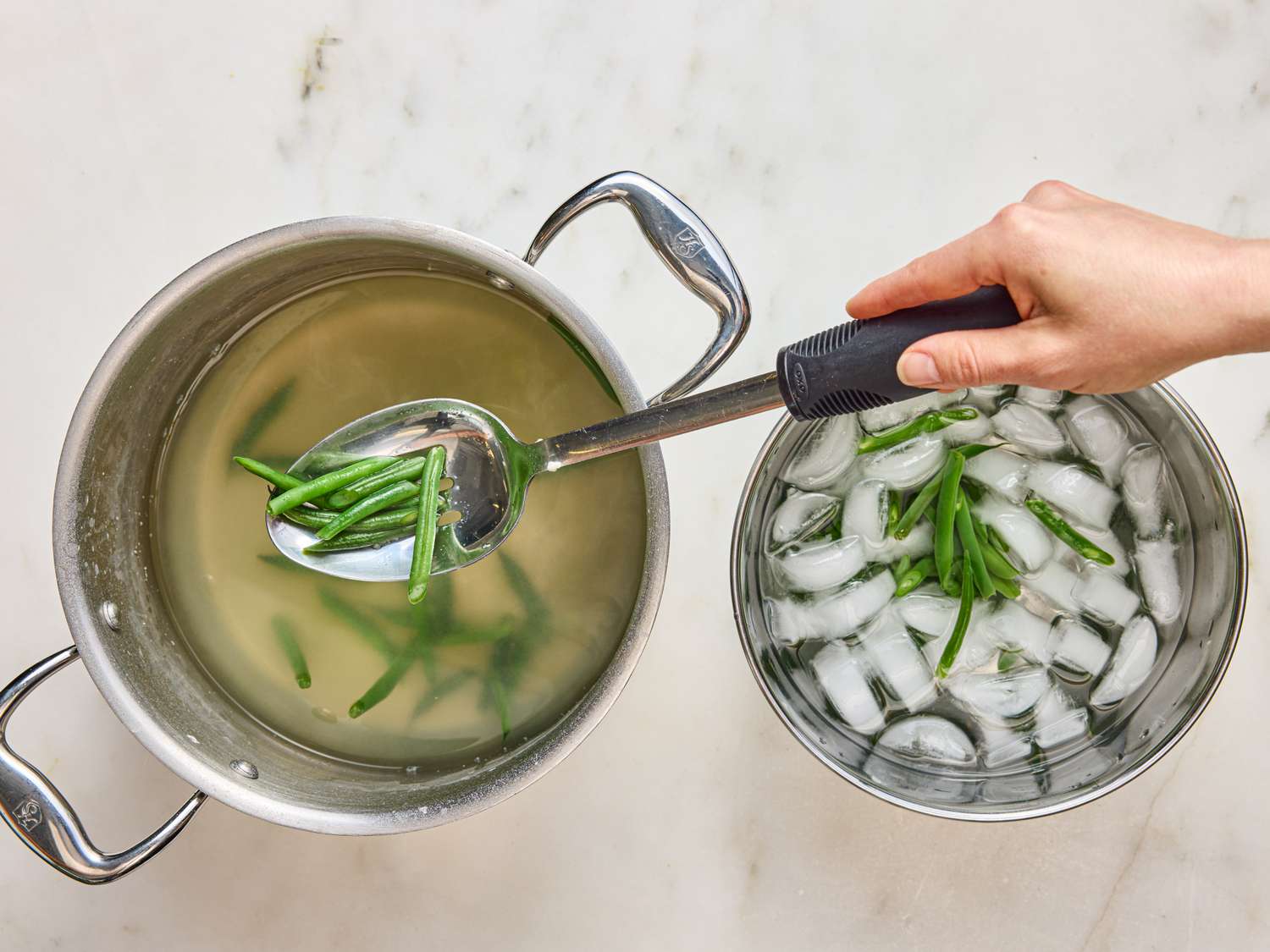 Blanching green beans in hot water and transferring to an ice bath to cool