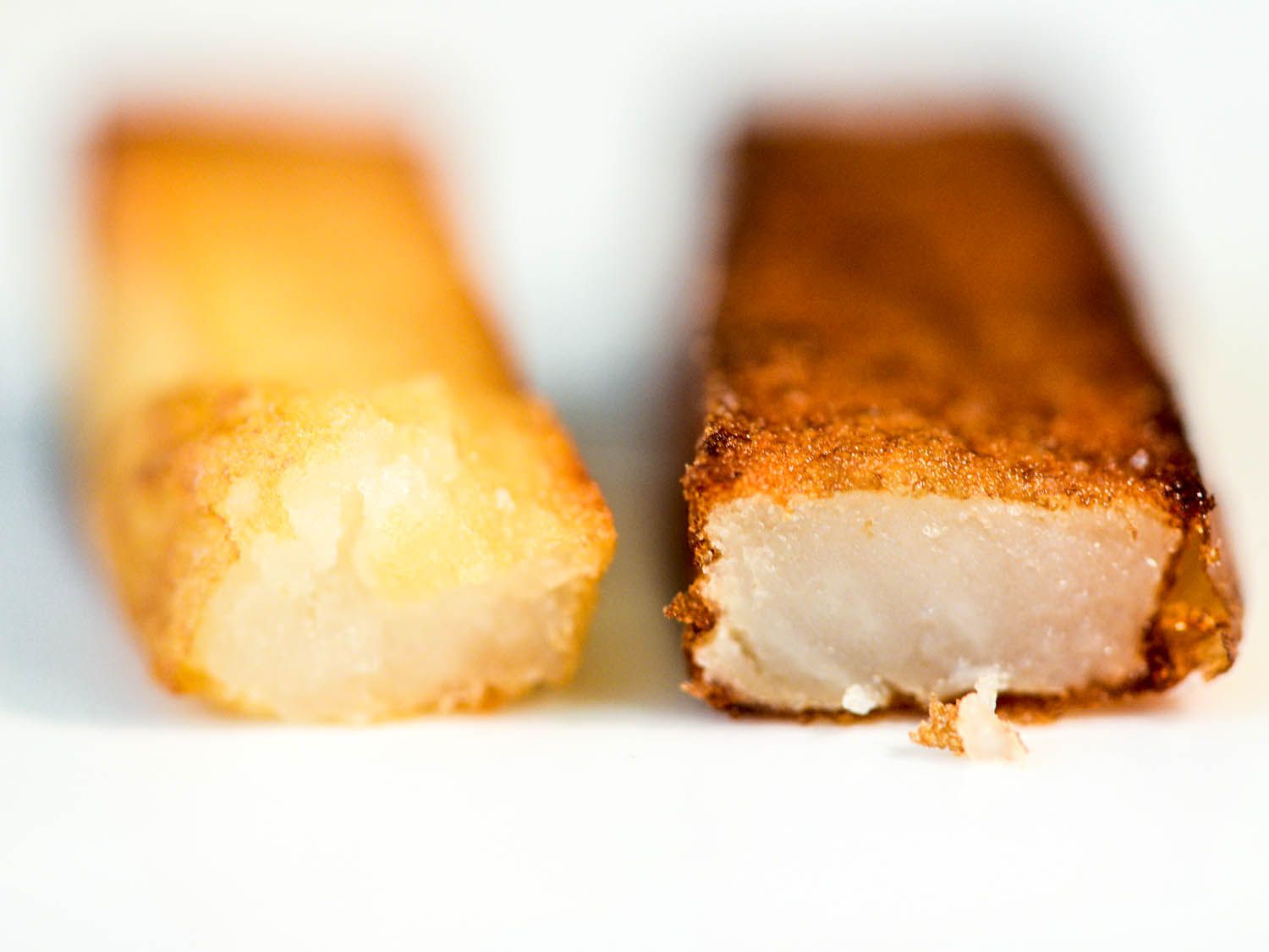 Close-up cross-section comparison of lighter golden pre-rinsed potato fry on the left and darker unrinsed fry on the right