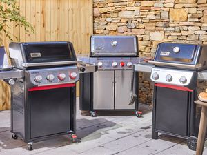 Three gas grills on an outdoor patio.