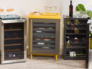 Three wine refrigerators, each styled differently, with glasses and bottles on top and inside.