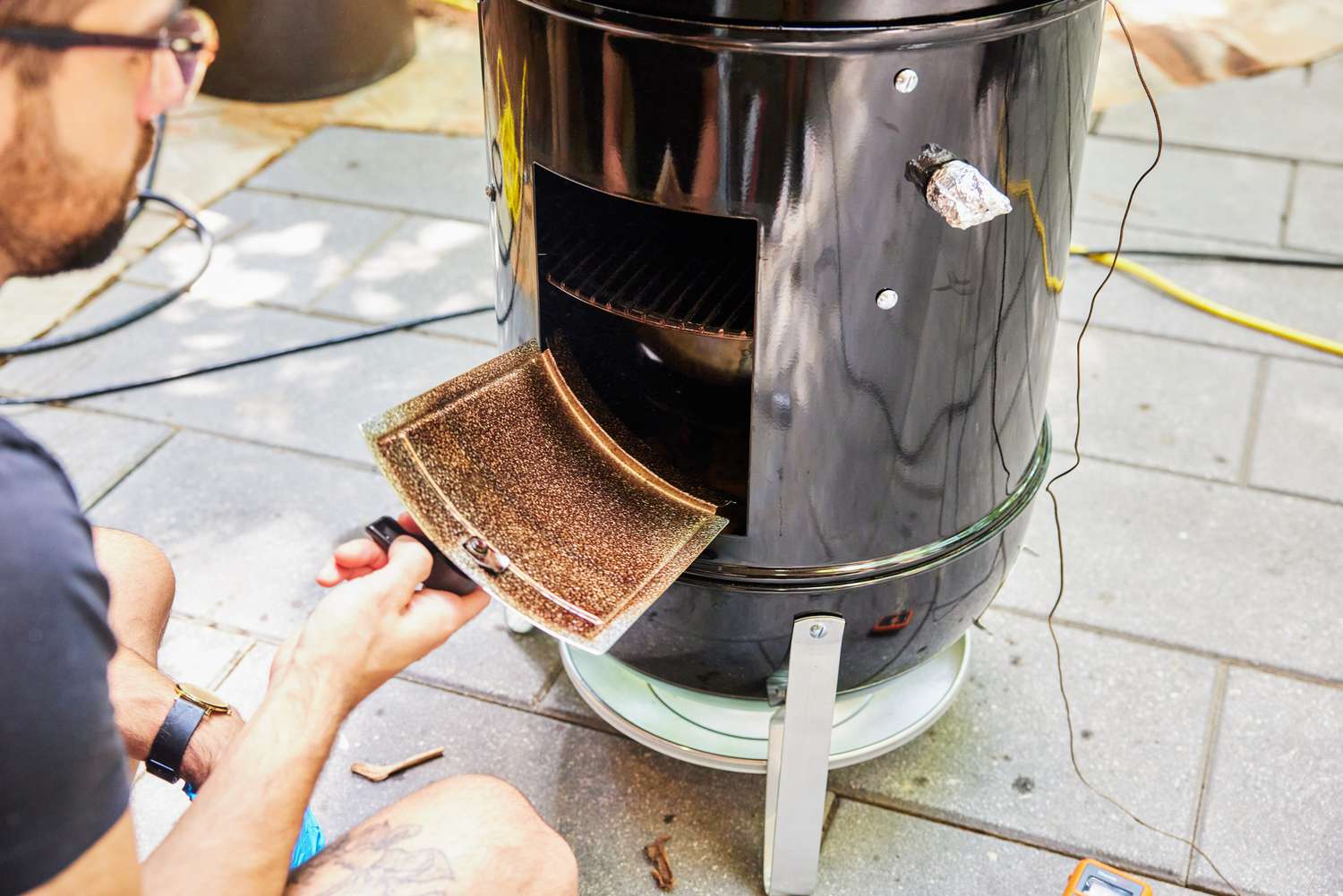 A person looks inside the Weber Smokey Mountain Cooker 18-Inch Charcoal Smoker (721001)