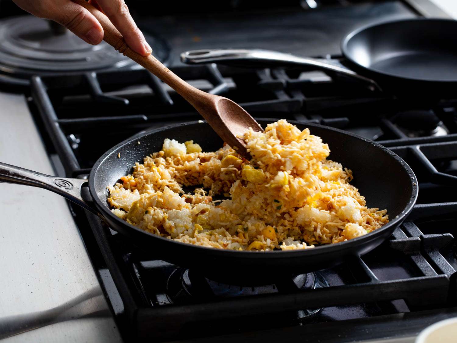 The hydrated crushed noodles are stirred into the pan.