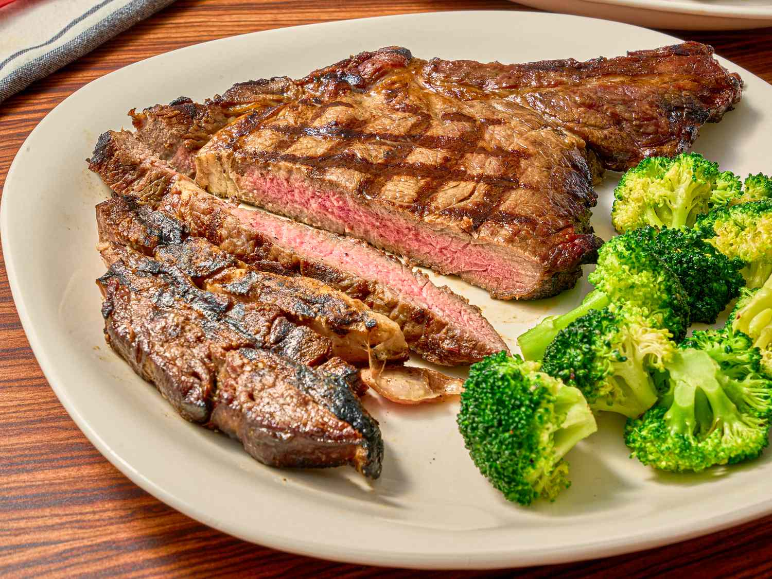 Grilled steak served sliced with a side of steamed broccoli on a plate