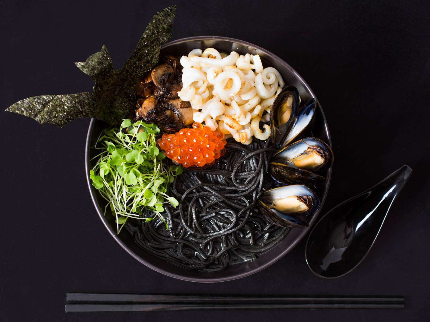 A bowl of seafood ramen with squid ink, mussels, and salmon roe