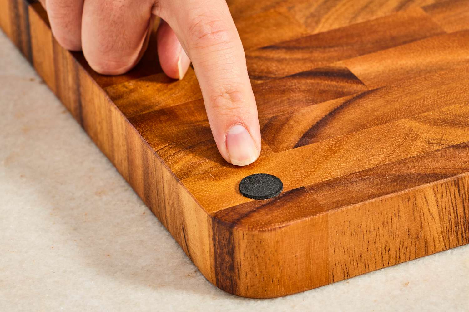 A person pointing to a rubber foot on a cutting board.