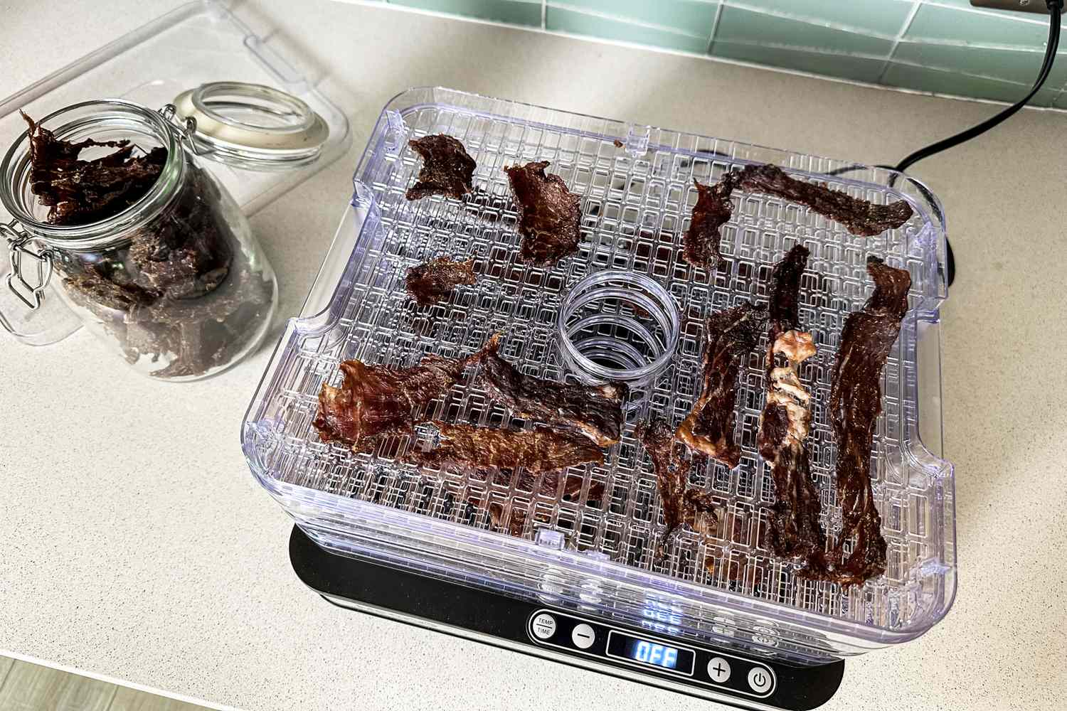 Nesco Digital 5 Rectangular Dehydrator with meat slices and a jar of jerky nearby