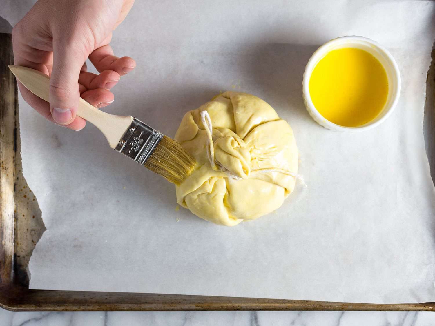 Brushing puff pastry parcel with egg wash for baked brie.
