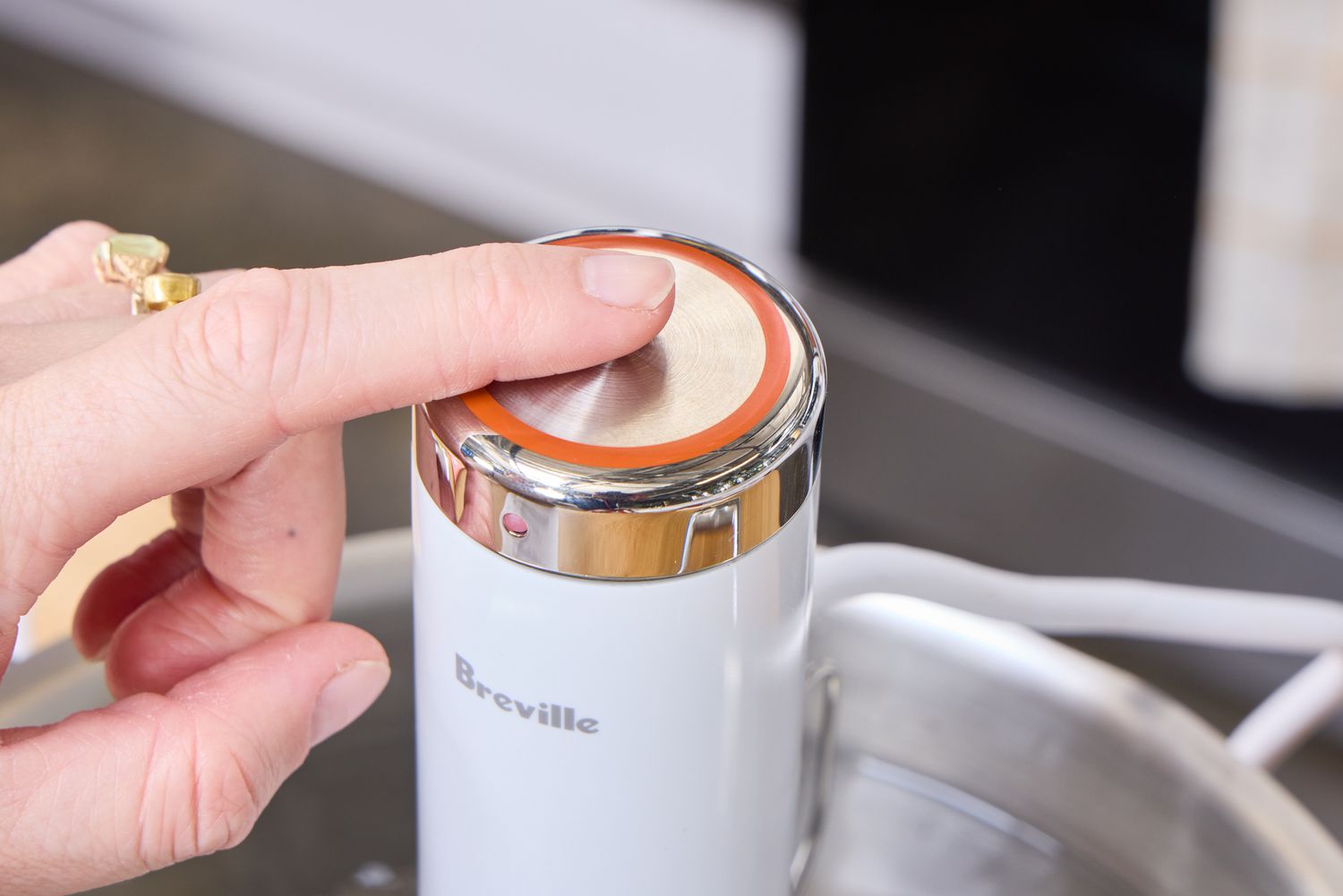 A person touches the top of the Breville Joule Turbo Sous Vide