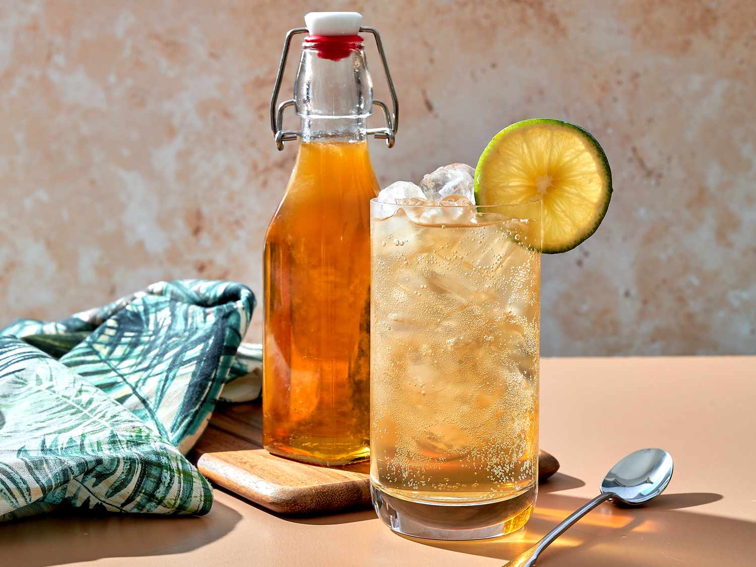 Tonic syrup combined with sparkling water in a glass with ice, bottle of tonic syrup in the backround