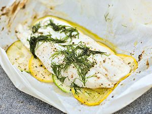 Fish grilled in parchment, with sliced yellow and green summer squash and plenty of dill on top.