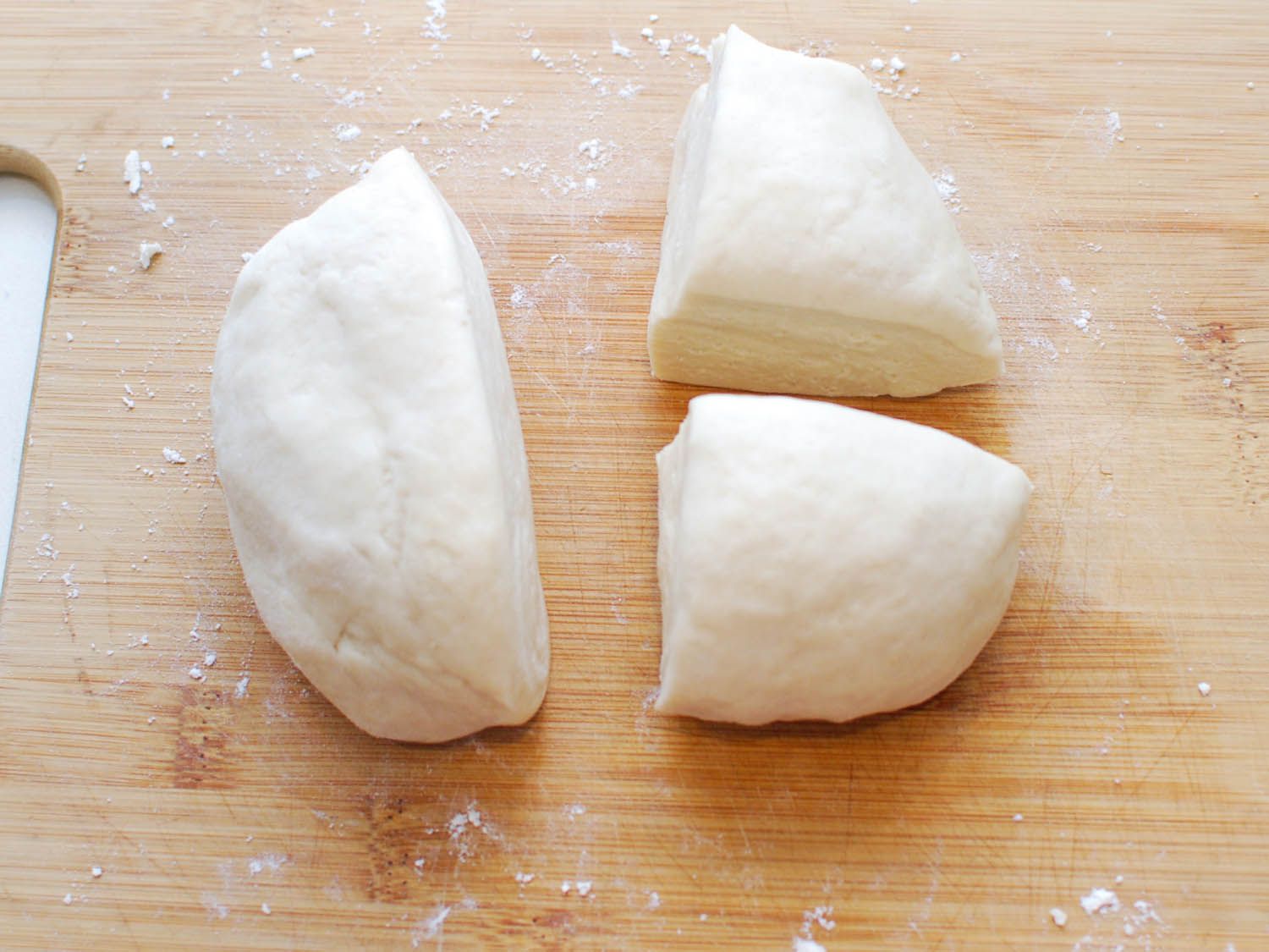 Sheng jian bao dough is cut into quarters.